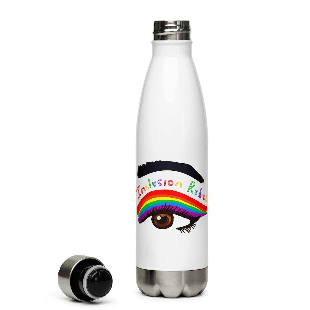 This is a photo of a white inclusion rebel water bottle that has a large colorful hand-drawn illustration of a right eye in the middle of the water bottle. There is an eyeliner design above their right eye. The design includes a series of lines drawn in the colors of the LGTB flag with the words, Inclusion Rebel, outlined in a handwriting style above the lines. The water bottle's cap is off lying next to the side of the bottle.