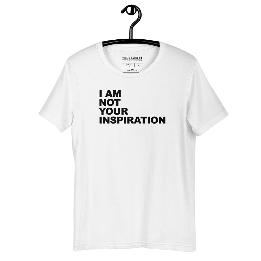 This is a white 'I Am Not Your Inspiration" t-shirt. On the top third of the inspiration shirt is the phrase, "I am not your inspiration," printed over four lines in black upper case letters. The tee shirt is hanging on a black hanger.