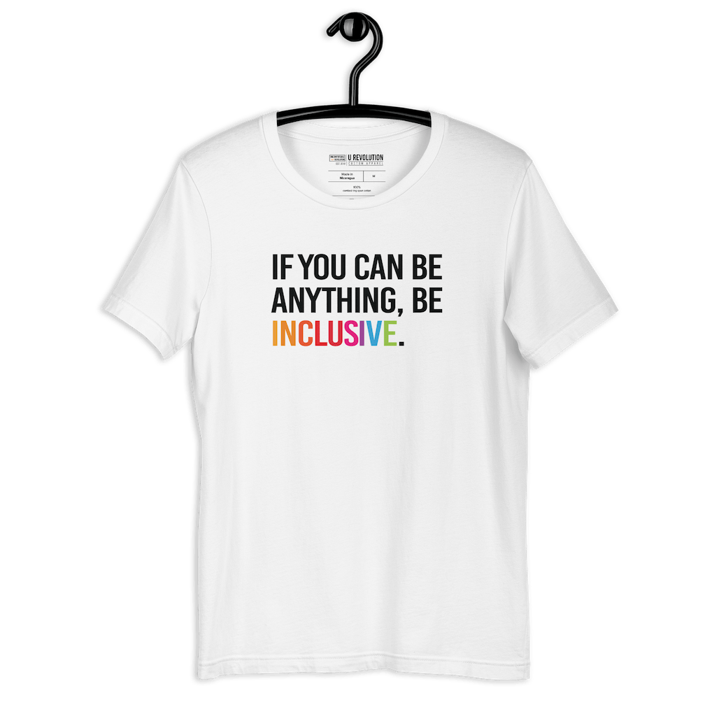 This is a photo of a white rainbow classic Be Inclusive tee. On the front of the inclusive t-shirt is the phrase: "If you can be anything, be inclusive," in black upper case letters. All the text is in black, except "Inclusive," which is in rainbow colors.