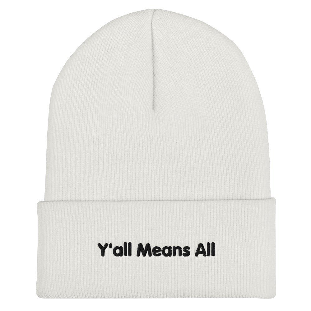 This is a photo of a white Y'all Means All beanie. On the front of the beanie the phrase, 'Y'all Means All,' is embroidered on it in black title case letters.